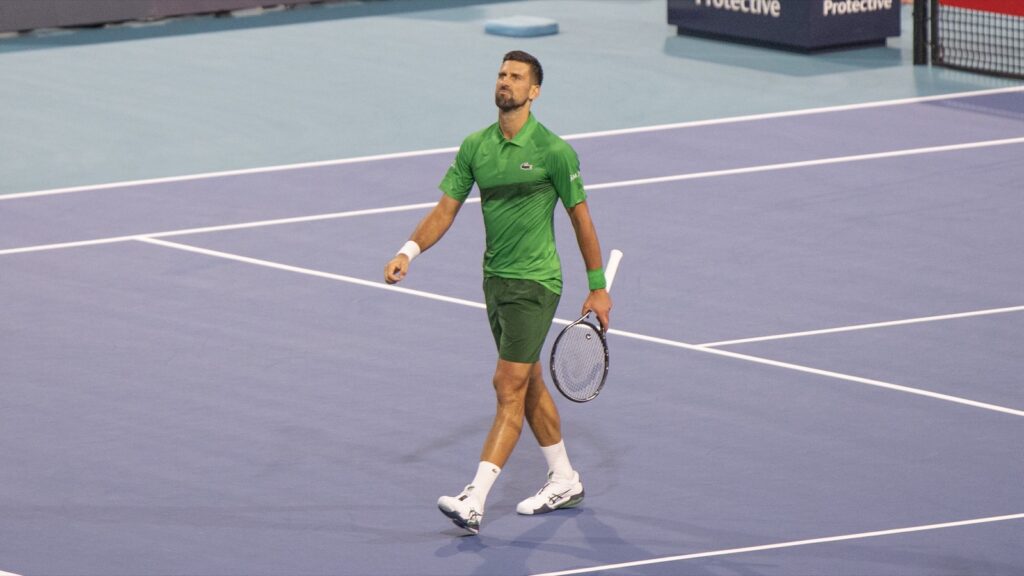 Novak Đoković u zelenoj majici hoda po terenu sa reketom u ruci na turniru u Majamiju.