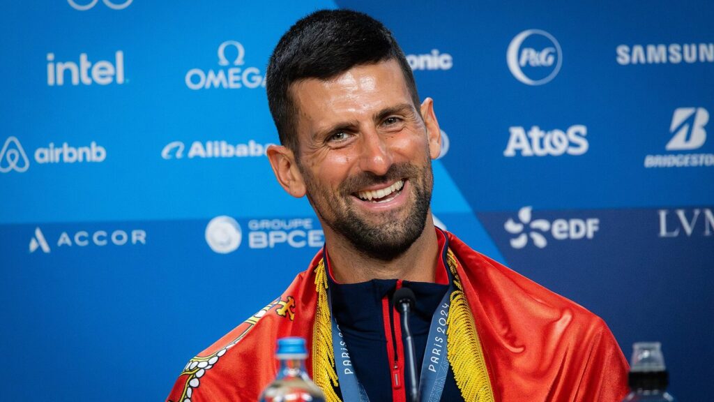 Novak Đoković sa zastavom Srbije na konferenciji za medije na Olimpijskim igrama u Parizu 2024.