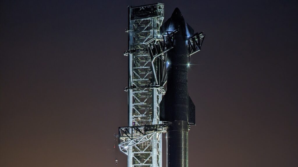 Raketa Starship noću stoji na lansirnoj rampi pored osvetljenog tornja u Starbejsu u Teksasu.