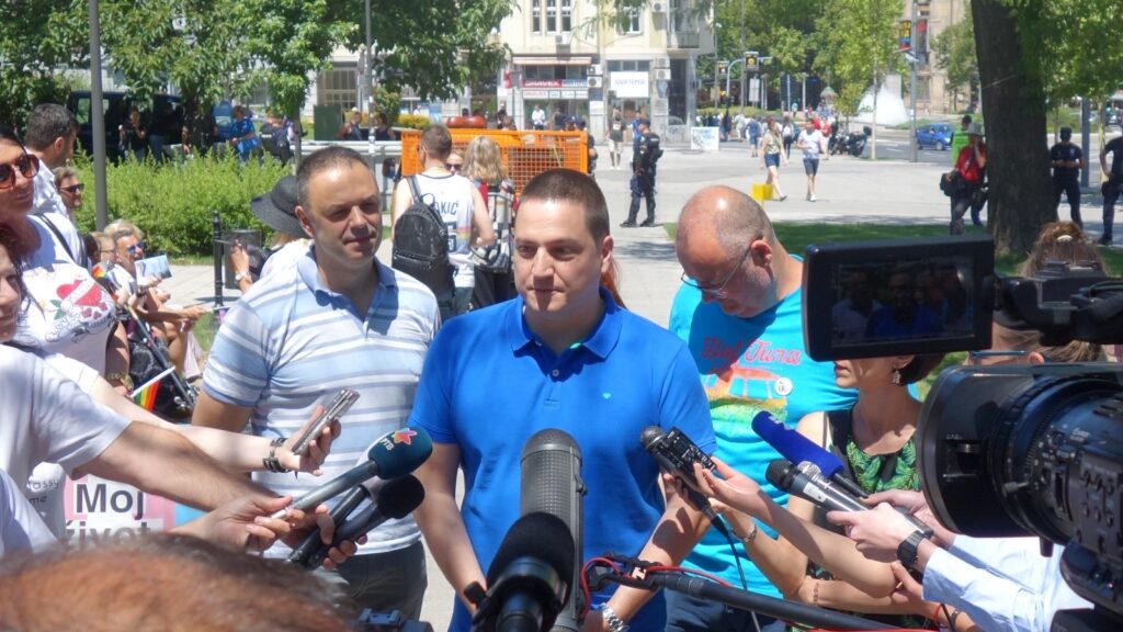 Branko Ružić u plavoj majici daje izjavu novinarima ispred mikrofona i kamera u parku u Beogradu