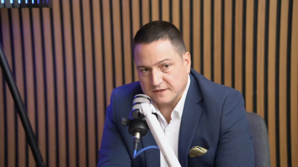 Branko Ružić u tamnoplavom sakou i beloj košulji govori za mikrofonom u studiju PodcastTv-a