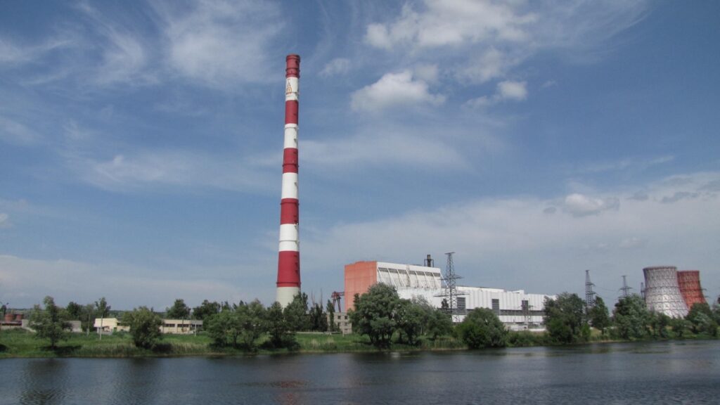 Termoelektrana-toplana 5 u Harkovu: crveno-beli dimnjak, glavna zgrada i rashladni tornjevi iza drveća, pogled preko vode