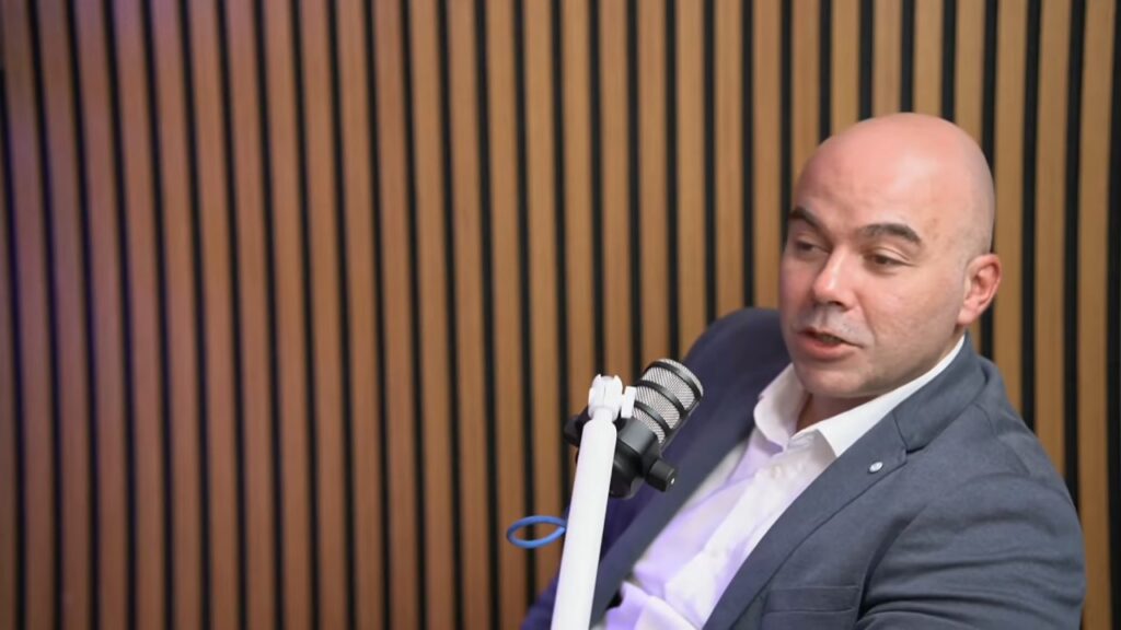 Ljubomir Stefanović, urednik „Slavija info“, u sivom sakou i beloj košulji govori za mikrofonom u studiju PodcastTv