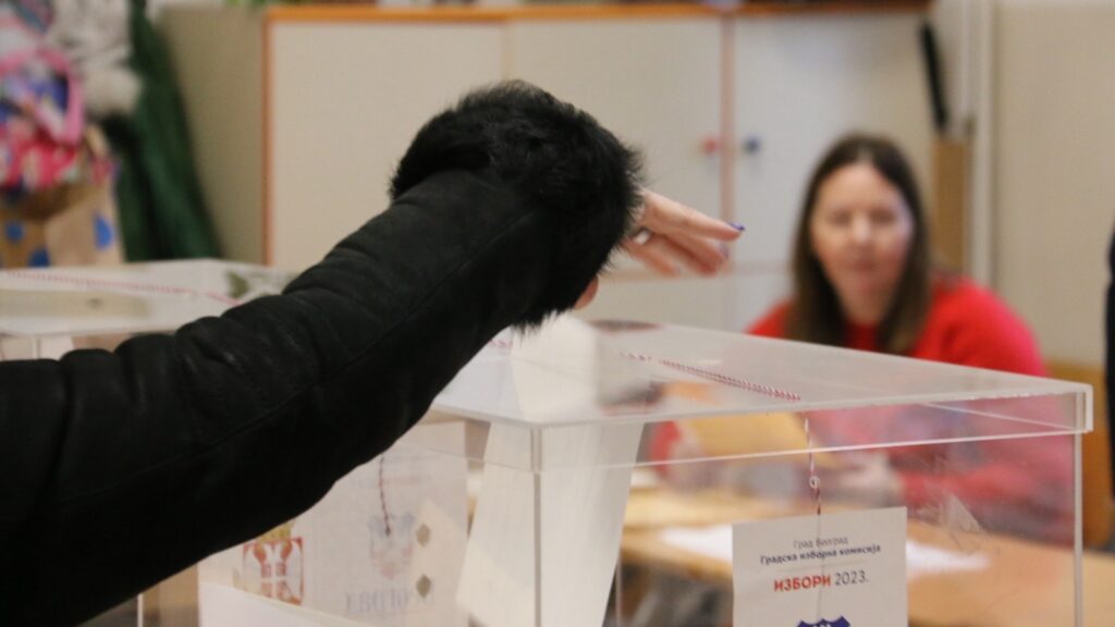 Birač ubacuje glasački listić u providnu glasačku kutiju sa natpisom Izbori 2023 na biračkom mestu u Beogradu