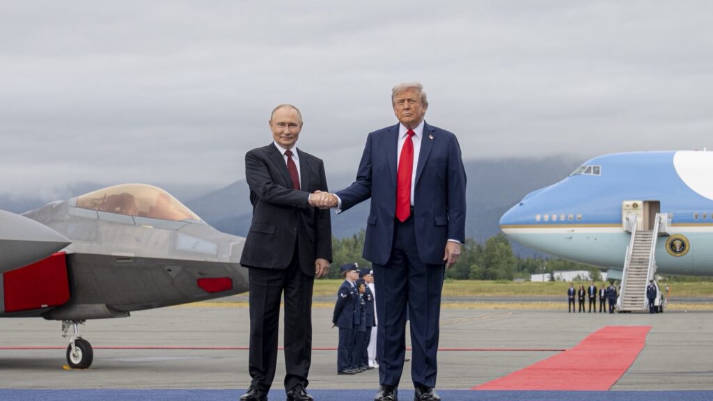 Donald Tramp i Vladimir Putin se rukuju na pisti vojne baze u Enkoridžu, iza njih borbeni avion i predsednički avion